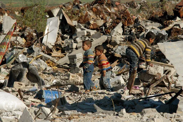 Three young boys pick their way across the rubble of a destroyed building in the Gaza Strip.