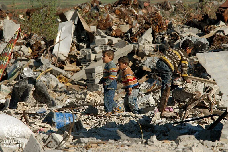 Three young boys pick their way across the rubble of a destroyed building in the Gaza Strip.