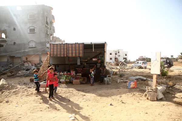 Children stand outside a small roadside shop among damaged buildings in the Gaza Strip.